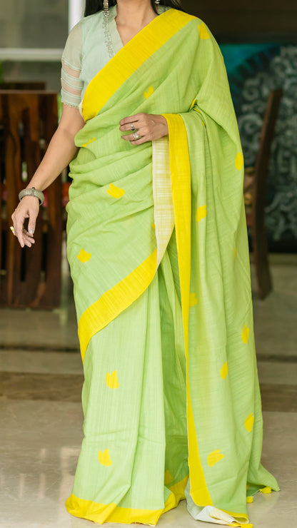 Lively green linen saree with bright yellow border, motifs and tassels.