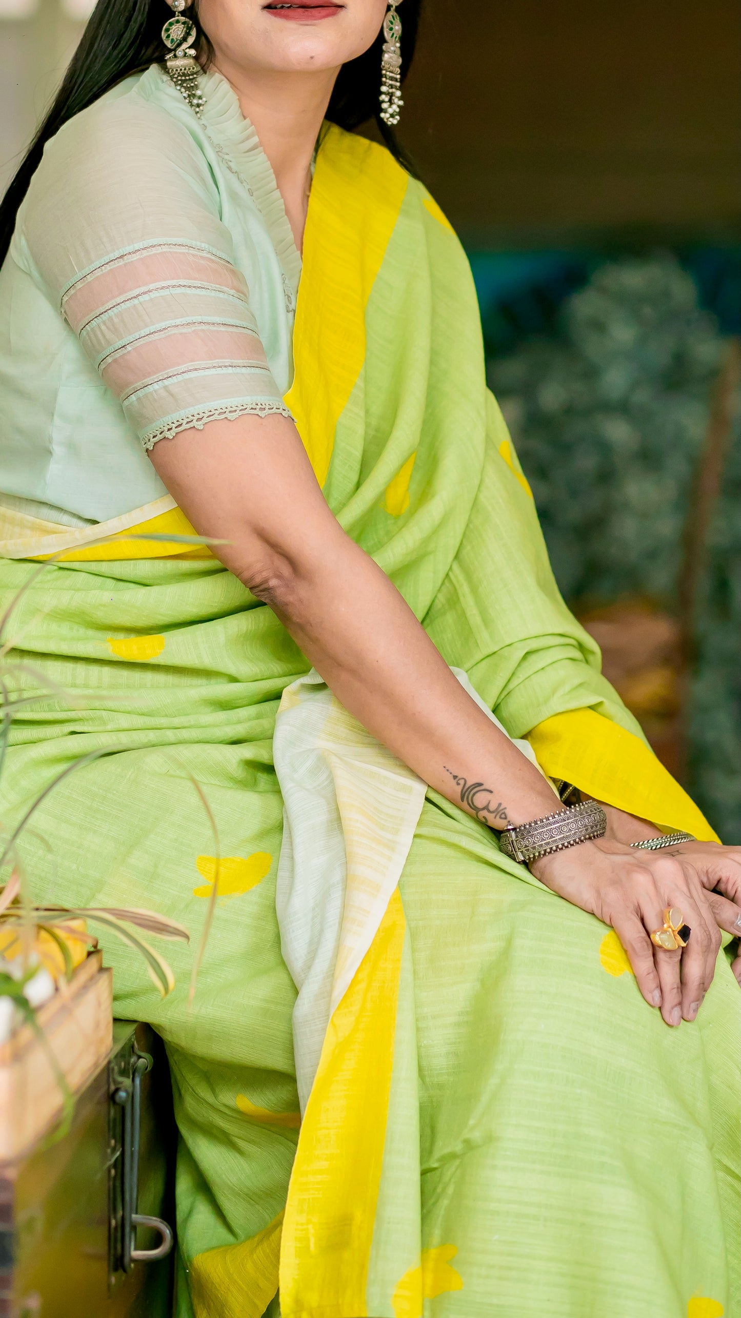 Lively green linen saree with bright yellow border, motifs and tassels.