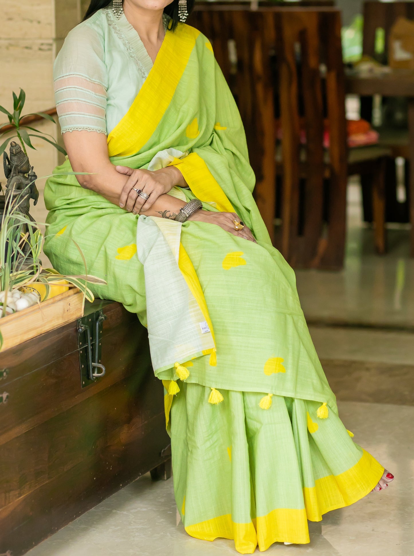 Lively green linen saree with bright yellow border, motifs and tassels.