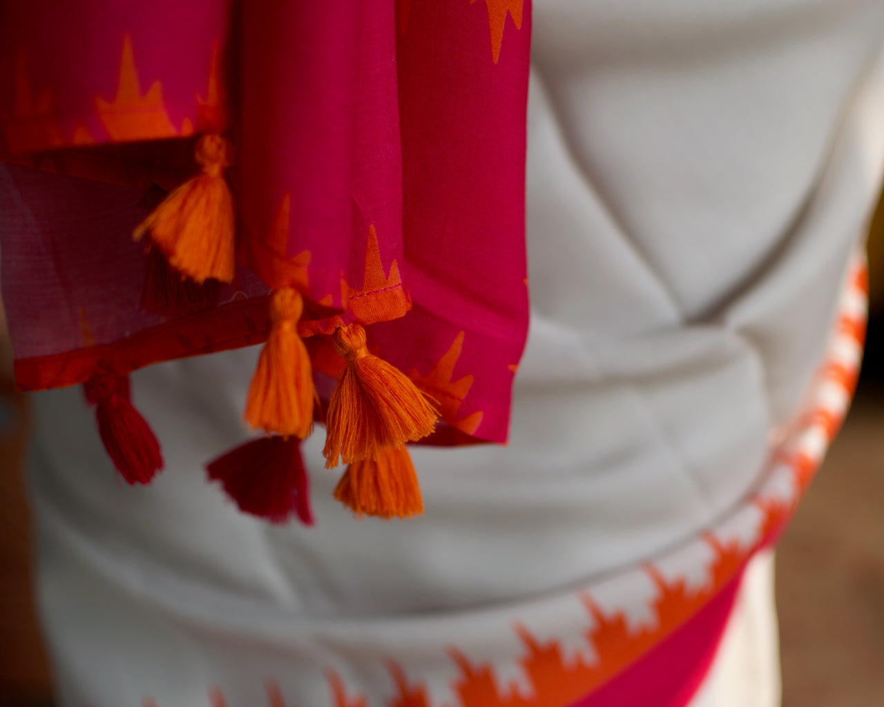 Muslin handcrafted, naturally dyed saree in a shade of white with popping colour combination of orange and pink.