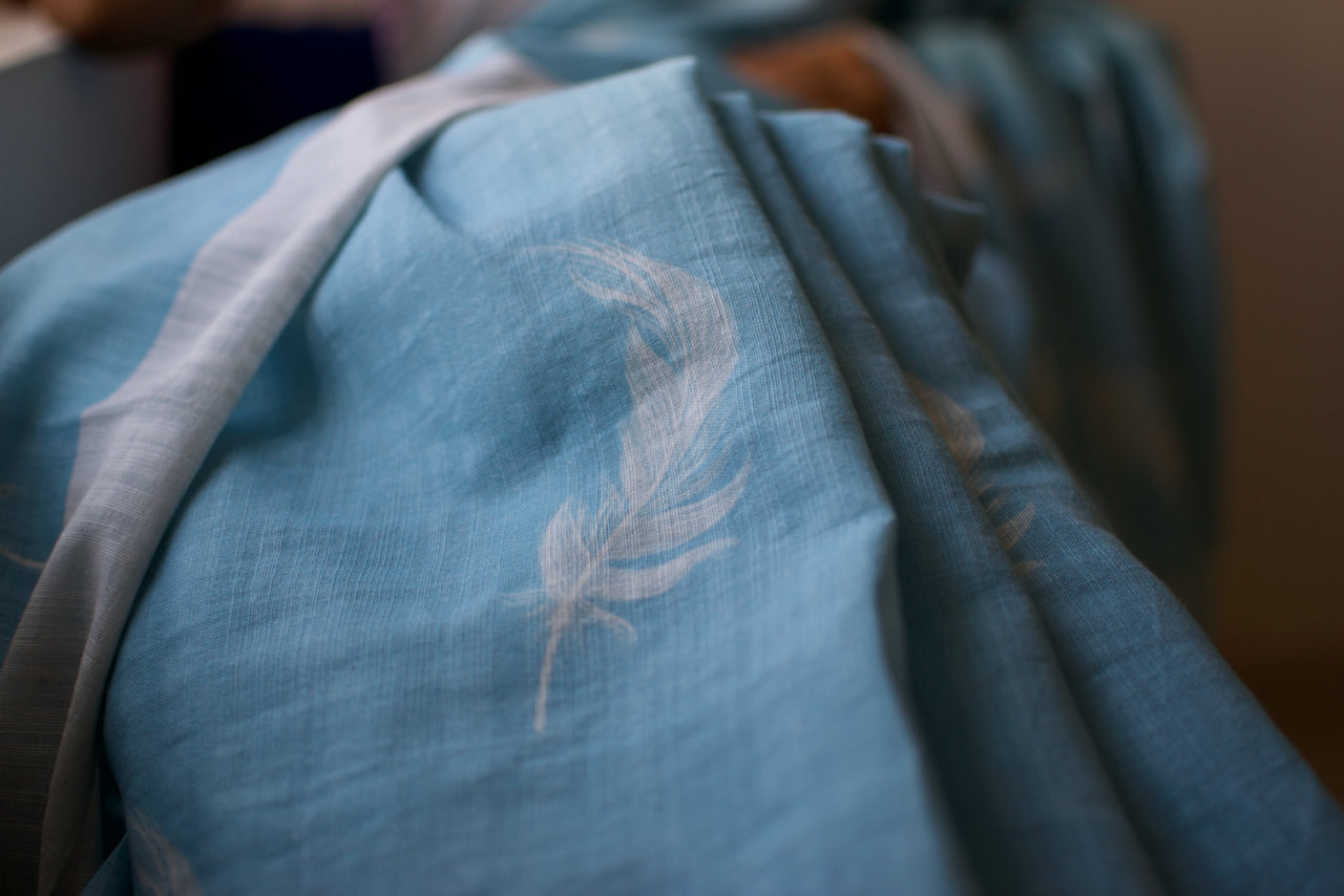 Linen Cotton handcrafted, naturally dyed saree in blue colour with white border and feather motifs.