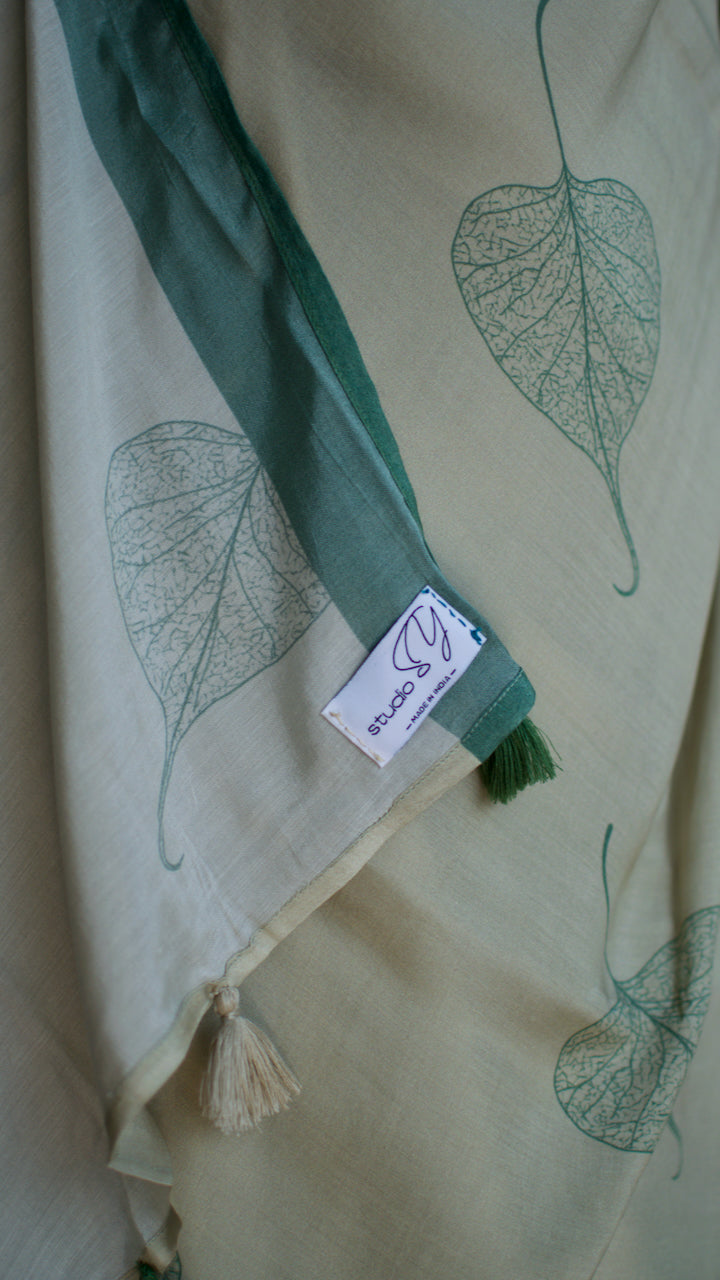 Muslin handcrafted, naturally dyed saree in a shade of beige with green border and pipal leaf motif.