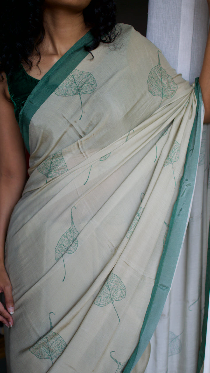 Muslin handcrafted, naturally dyed saree in a shade of beige with green border and pipal leaf motif.